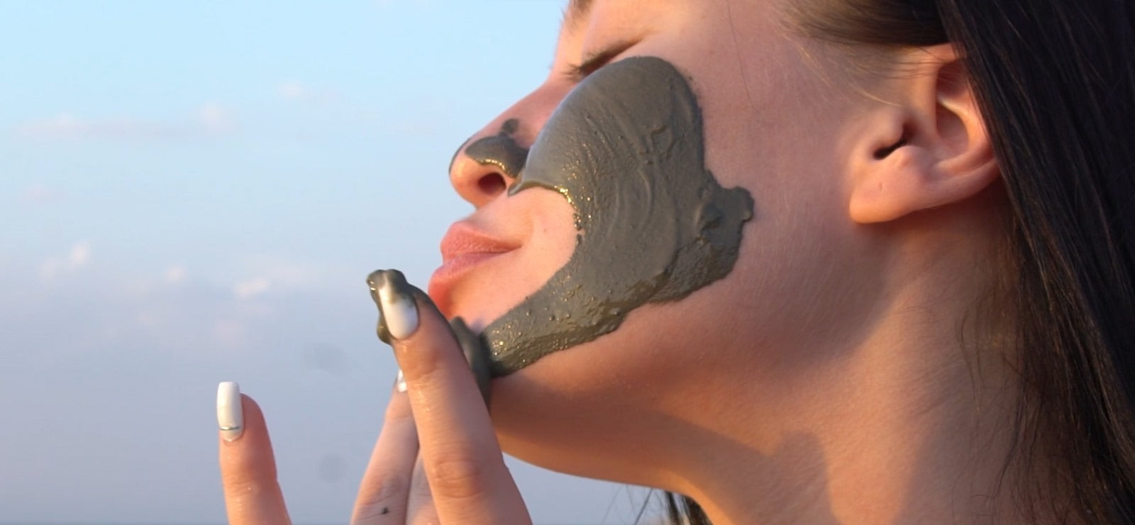 Woman applying Bloom Dead Sea Mud Mask, showcasing smooth application of the mineral-rich skincare product for a refreshed complexion